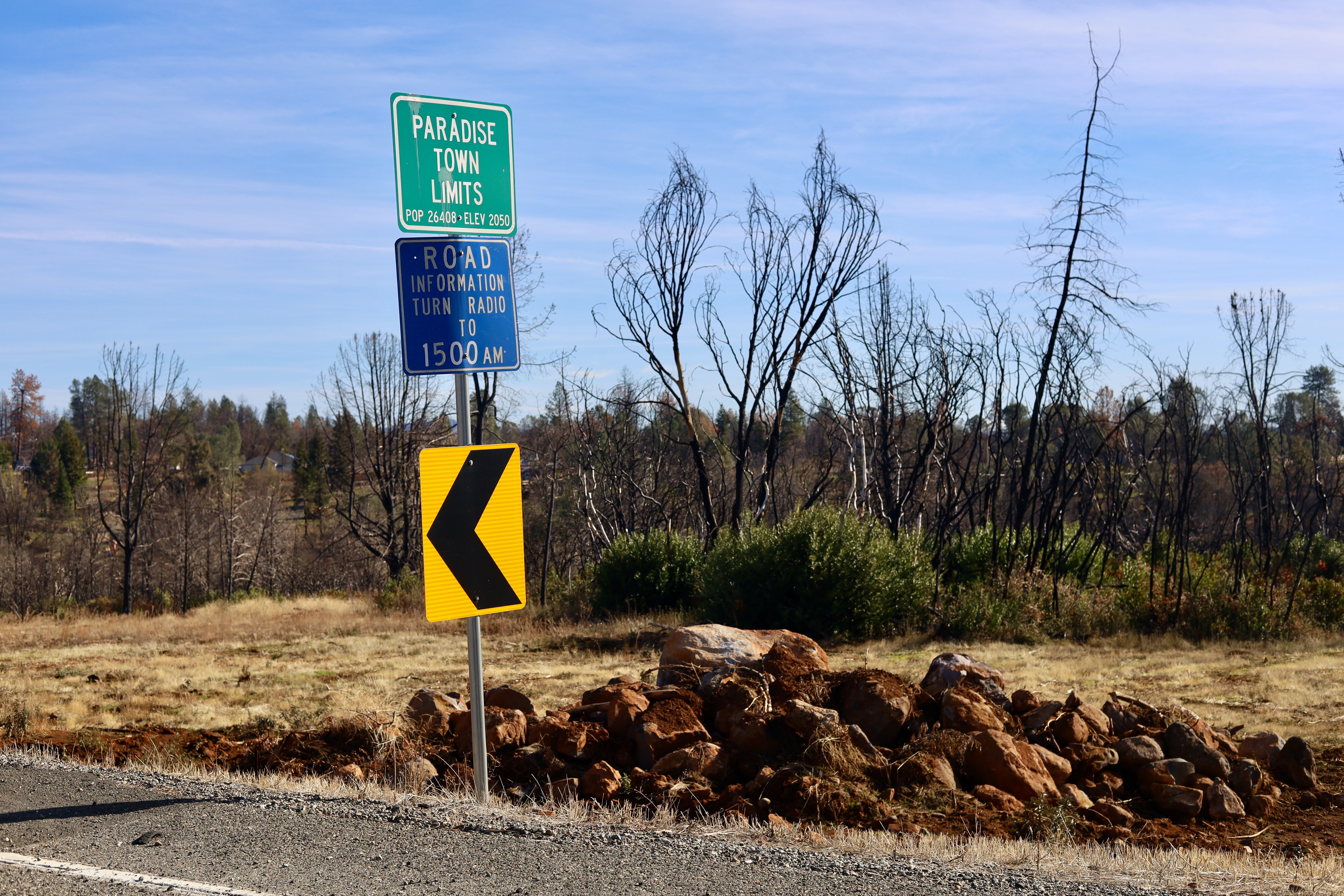 photo of yellow, green, and blue road signs at town limit of Paradise, CA.